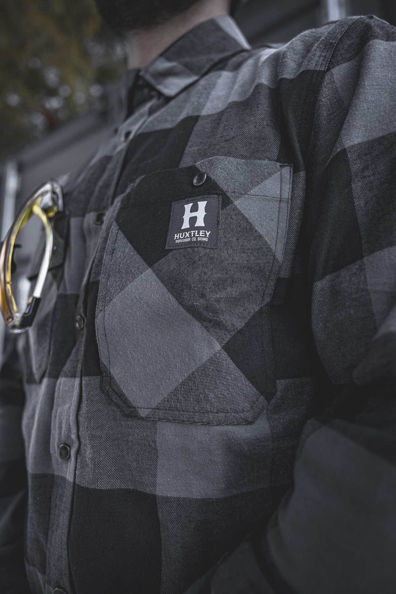
                  
                    Up-close view of the Huxtley HD-57 Flex Flannel in Charcoal/Black, highlighting the chest pocket stitching and iconic Huxtley Workwear logo. Built for tradesmen who take pride in their gear.
                  
                