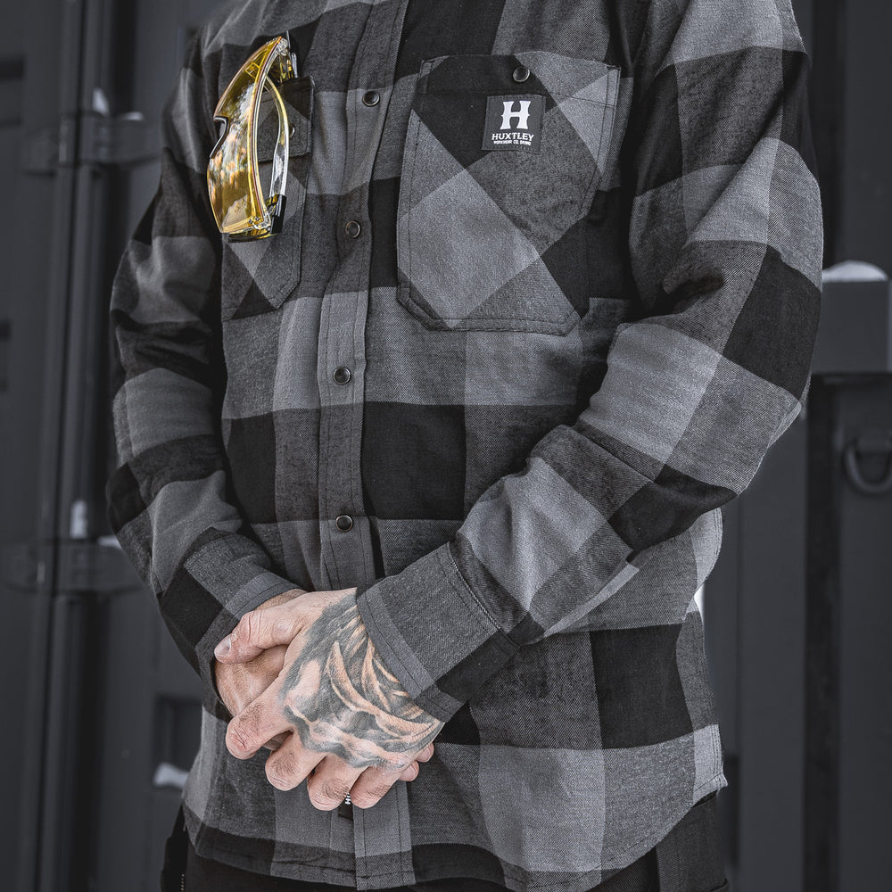 
                  
                    The Huxtley HD-57 Flex Flannel in Charcoal/Black delivers a durable, stretch-built fit with work-ready storage and style. Shown here with safety glasses tucked into the chest pocket—this flannel’s made for the grind.
                  
                