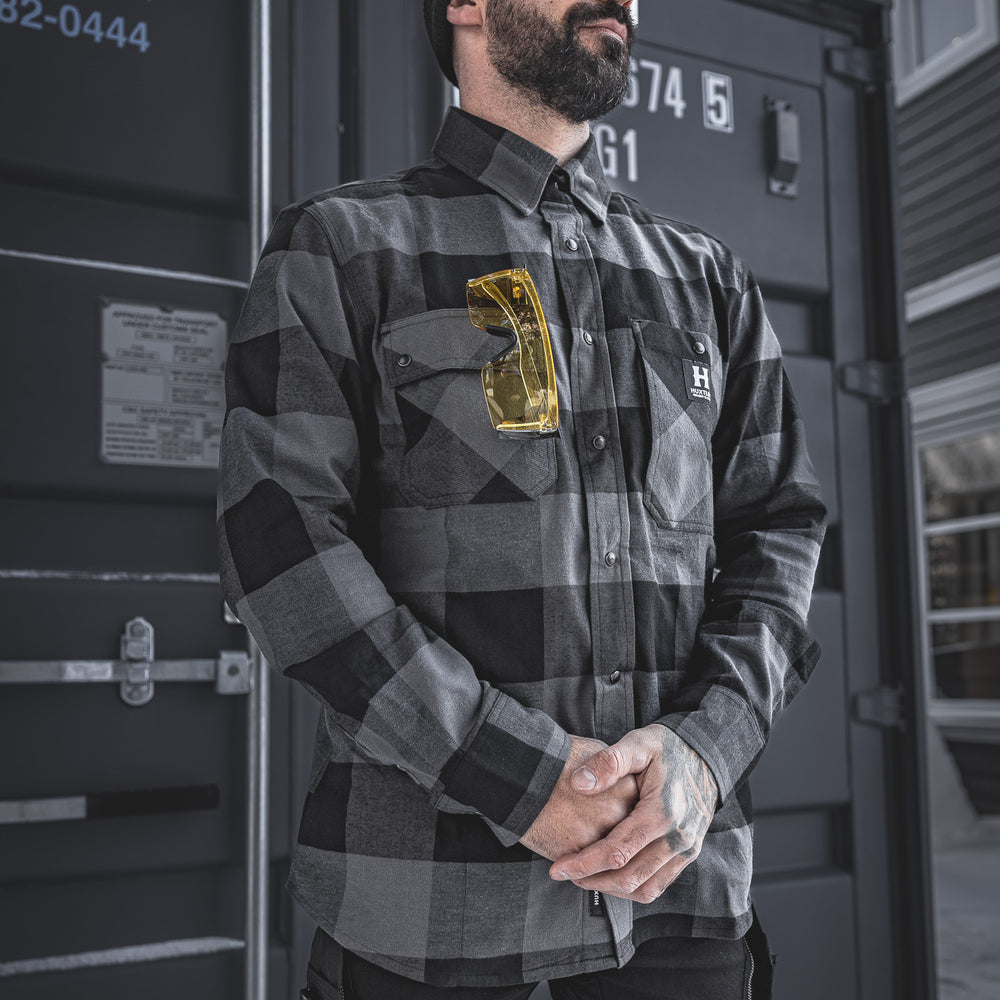 
                  
                    The Huxtley HD-57 Flex Flannel in Charcoal/Black shown in a real-world jobsite setting. With its rugged fit, stretch flannel build, and functional pocketing, it’s made to handle the cold and keep you moving.
                  
                