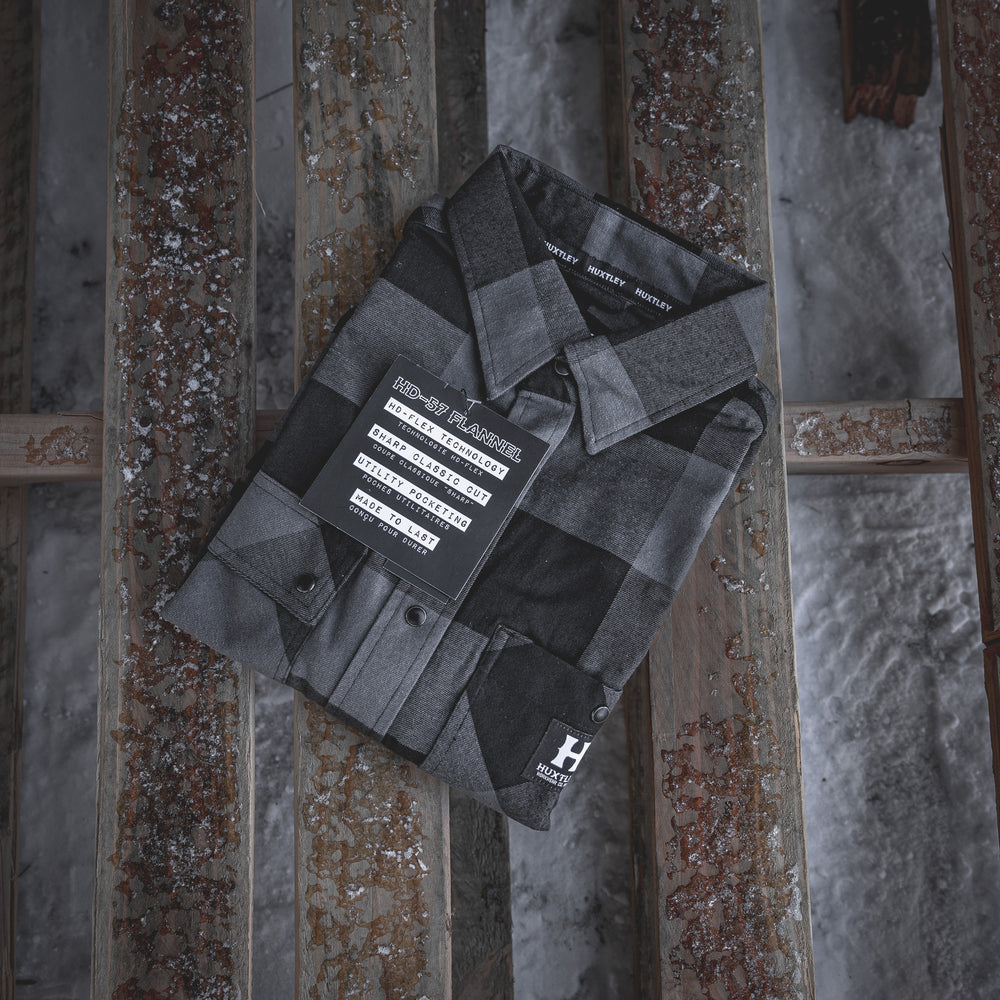 
                  
                    Folded presentation of the Huxtley HD-57 Flex Flannel in Charcoal/Black, featuring HD-Flex technology, sharper tailoring, and utility-focused design. Engineered for the trades, packed and ready for the grind.
                  
                