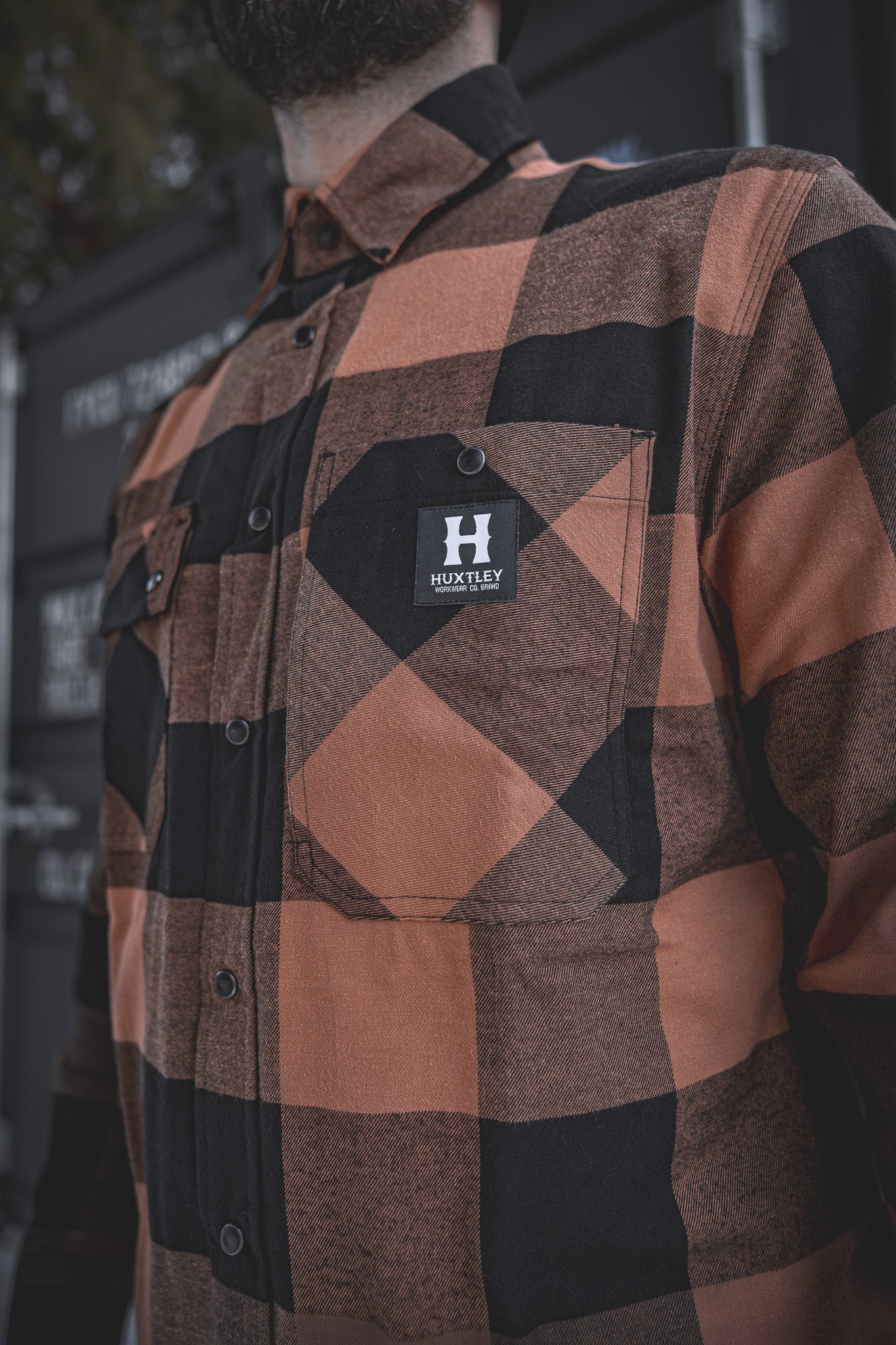 
                  
                    Close-up of the Huxtley HD-57 Flex Flannel in Whiskey/Black, showcasing the signature chest pocket with branded snap and bold buffalo check pattern. Built tough with attention to every detail.
                  
                