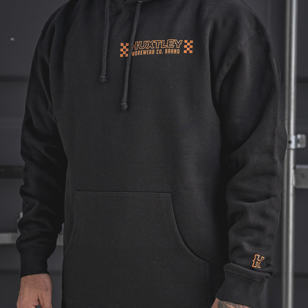 Stay sharp in the Huxtley Work Hard Have Fun Hoodie. This clean front view shows off the orange checkerboard Huxtley Workwear Co. logo and embroidered sleeve “H” – perfect blend of grit and style on the jobsite.