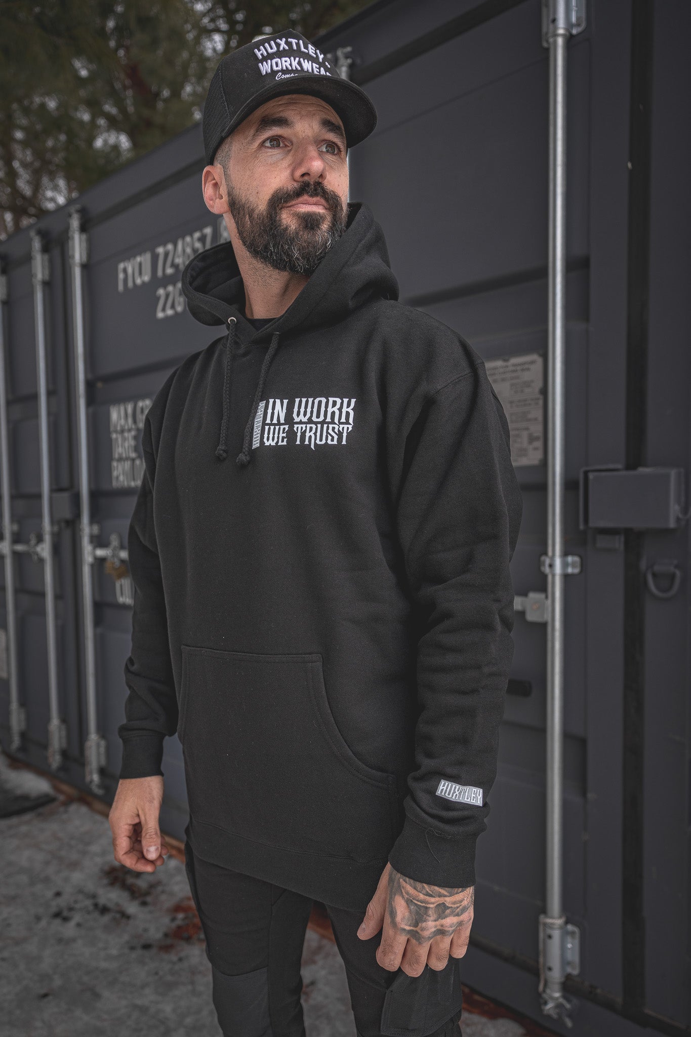 
                  
                    Model wearing the In Work We Trust Hoodie in black. Gothic chest print, relaxed fit, and branded sleeve tag. Built for grit, styled for the site.
                  
                