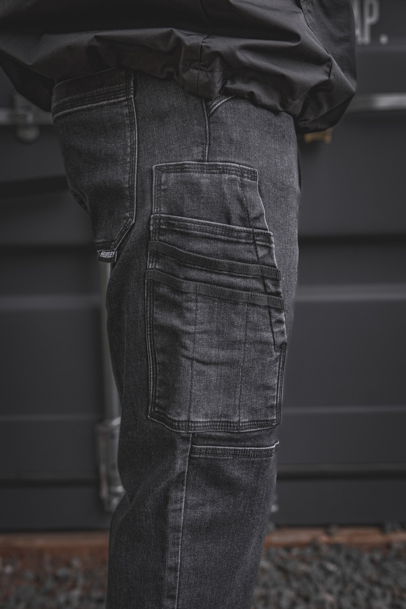 
                  
                    Detailed view of the RX-1 Relaxed Work Jeans in Stonewashed Black, highlighting the multi-tool side pocket built for phones, small tools, or meters.
                  
                