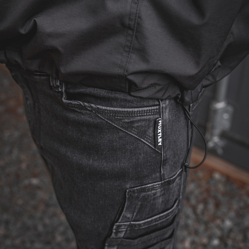 
                  
                    Detailed close-up of the RX-1 Relaxed Work Jeans in Stonewashed Black, featuring the signature HUXTLEY tag and multi-layer utility pocket built for jobsite performance.
                  
                