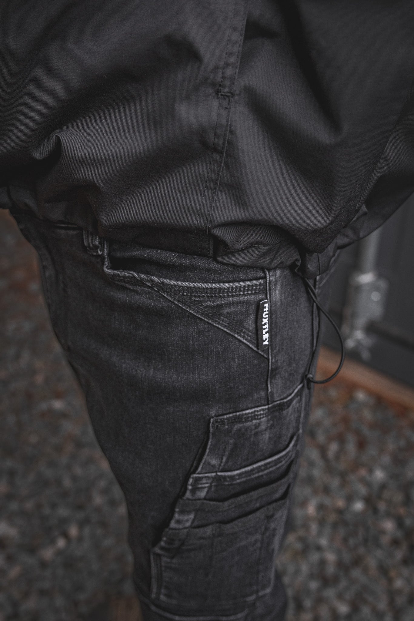 
                  
                    Detailed close-up of the RX-1 Relaxed Work Jeans in Stonewashed Black, featuring the signature HUXTLEY tag and multi-layer utility pocket built for jobsite performance.
                  
                