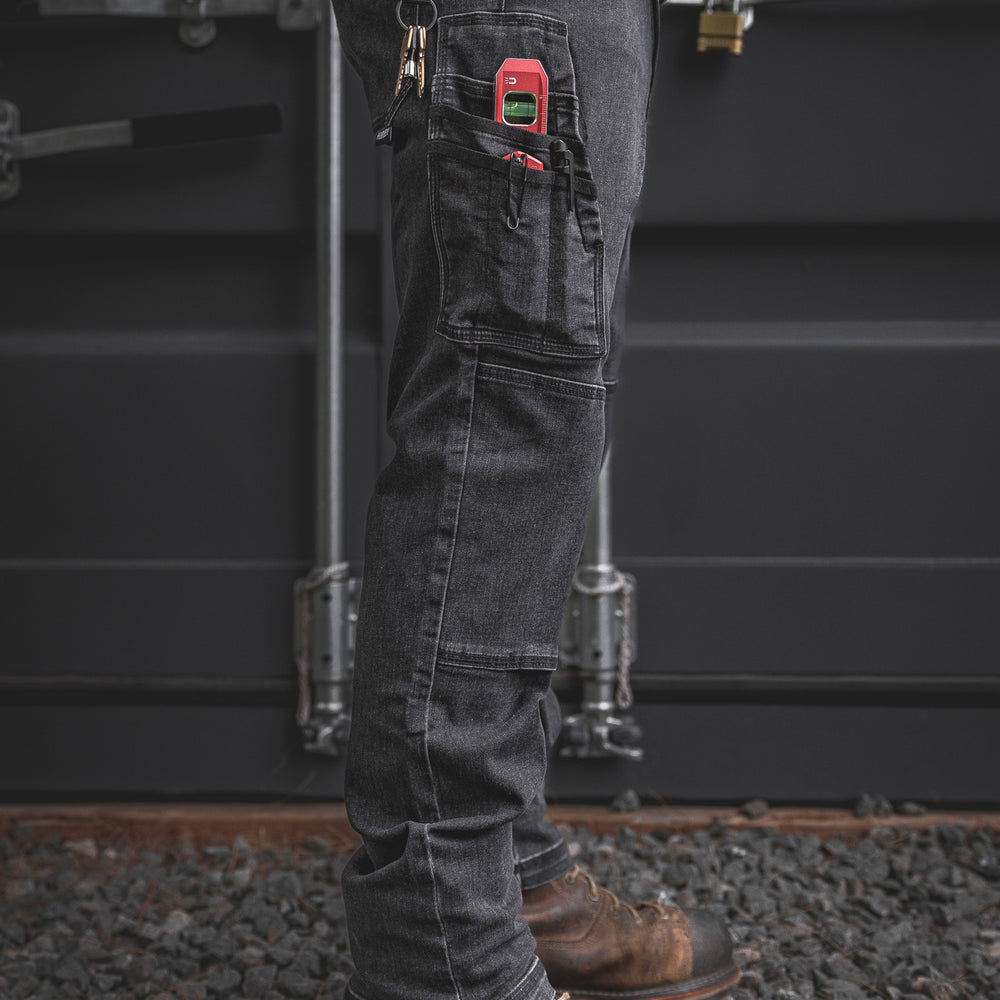 
                  
                    Full leg side shot of the RX-1 Relaxed Work Jeans in Stonewashed Black. Loaded with jobsite gear in the utility pocket and paired with steel toe boots—built to grind from site to shop.
                  
                