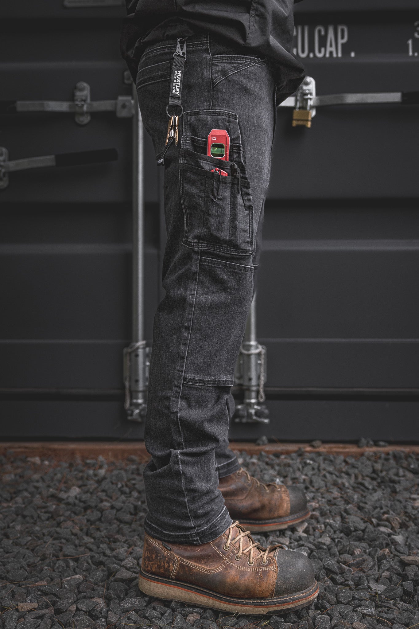
                  
                    Full leg side shot of the RX-1 Relaxed Work Jeans in Stonewashed Black. Loaded with jobsite gear in the utility pocket and paired with steel toe boots—built to grind from site to shop.
                  
                