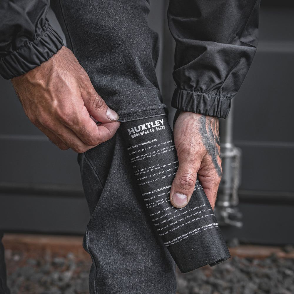 
                  
                    The RX-1 Relaxed Work Jeans in Stonewashed Black shown with a kneepad being inserted into the dedicated knee slot. Engineered for jobsite protection and all-day durability.
                  
                
