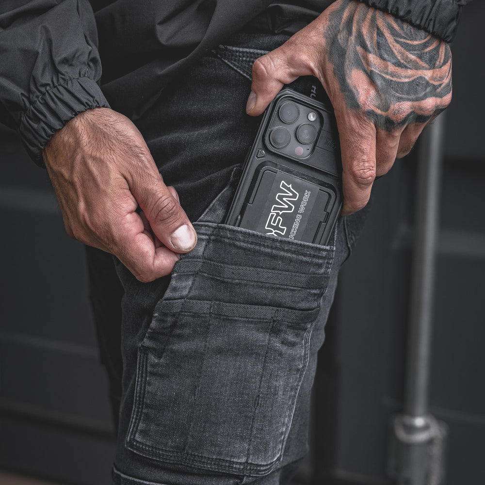 
                  
                    Close-up of the RX-1 Relaxed Work Jeans in Stonewashed Black, featuring the model sliding a rugged phone into the dedicated thigh pocket. Built to carry tools or your phone with ease on the jobsite.
                  
                