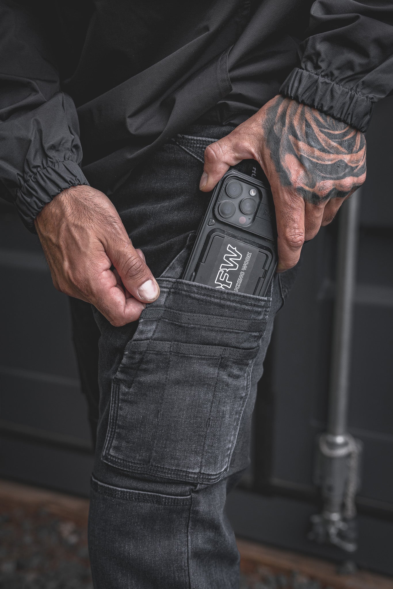 
                  
                    Close-up of the RX-1 Relaxed Work Jeans in Stonewashed Black, featuring the model sliding a rugged phone into the dedicated thigh pocket. Built to carry tools or your phone with ease on the jobsite.
                  
                