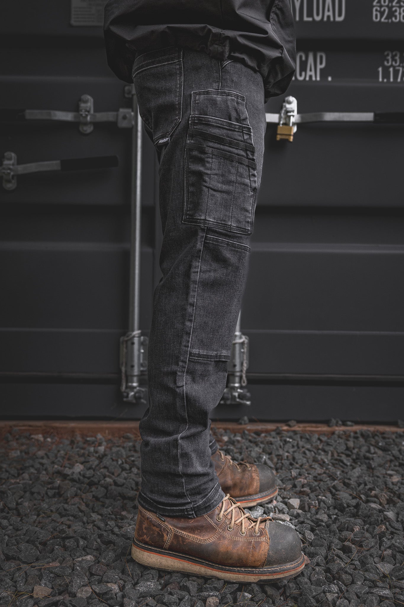 
                  
                    Side view of the RX-1 Relaxed Work Jeans in Stonewashed Black, featuring stacked utility pockets and articulated knees for everyday worksite performance.
                  
                