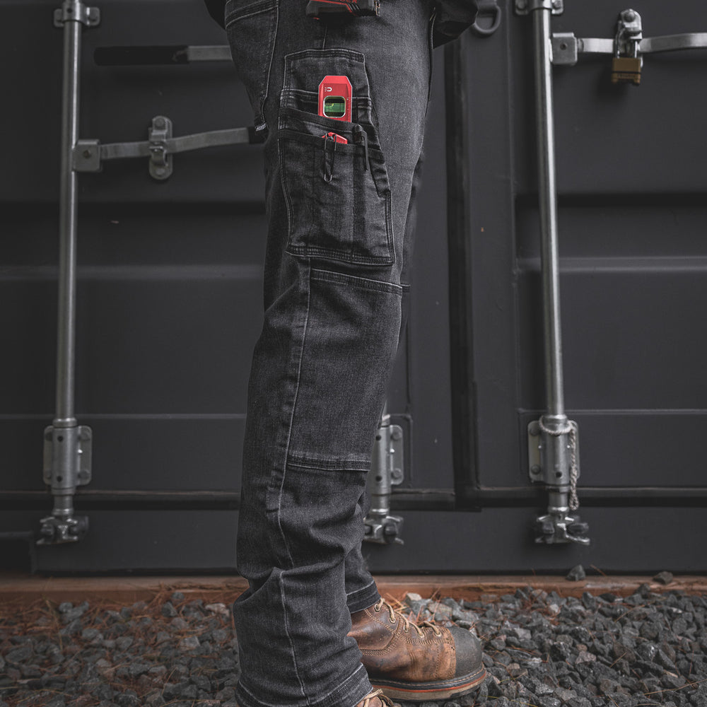 
                  
                    Side profile of the RX-1 Relaxed Work Jeans in Stonewashed Black, fully loaded with a laser level, utility knife, and tape measure. Built tough for jobsite performance with work-ready functionality.
                  
                