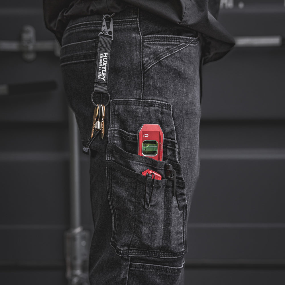 
                  
                    Close-up of the RX-1 Relaxed Work Jeans in Stonewashed Black showing off the side tool pocket and Huxtley-branded key clip. Built for trades with rugged stretch denim and jobsite-ready storage.
                  
                