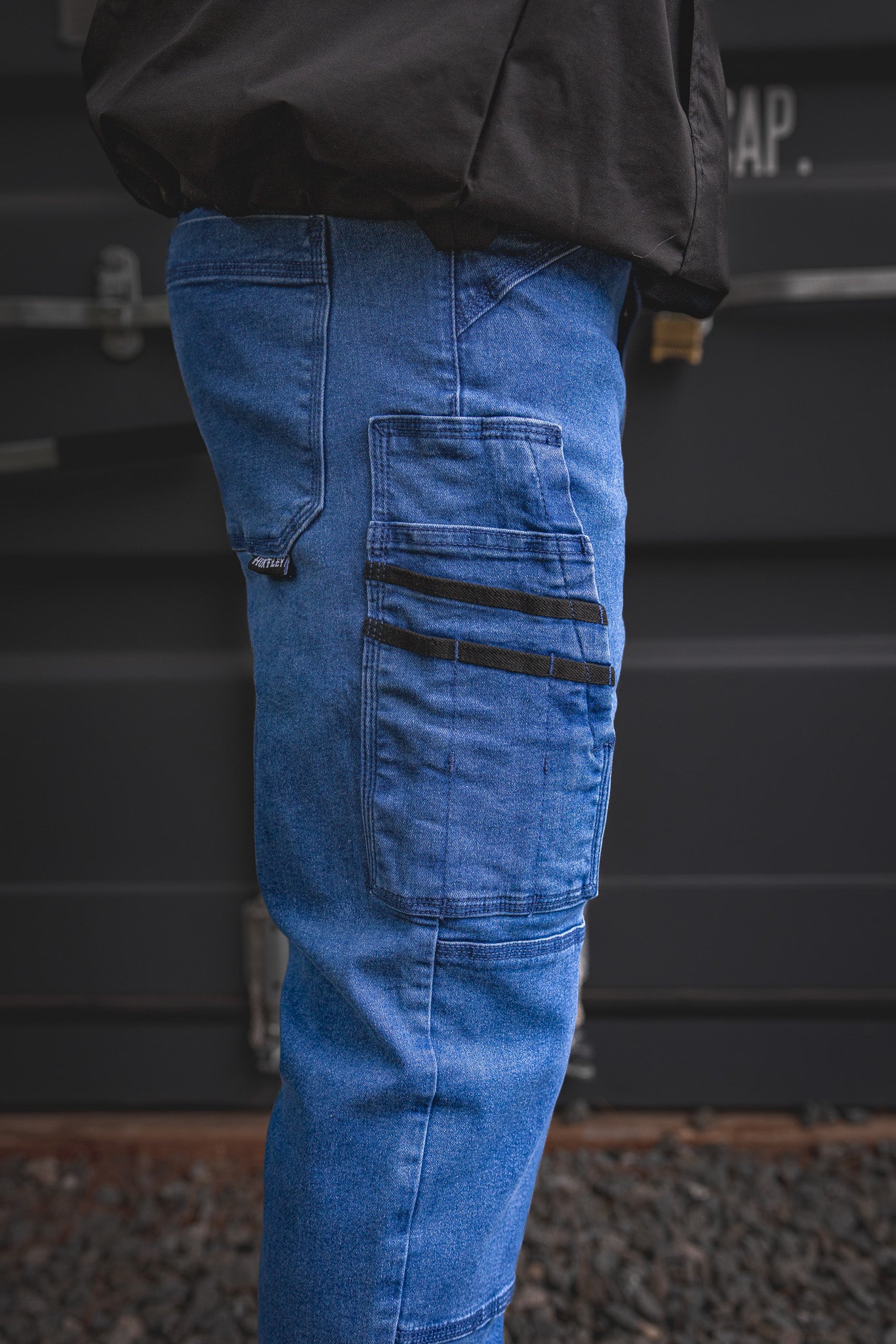 
                  
                    Zoomed-in detail of the RX-1 Relaxed Work Jeans in Stonewashed Blue, showing reinforced tool pocket design with black utility straps—engineered for performance on-site.
                  
                