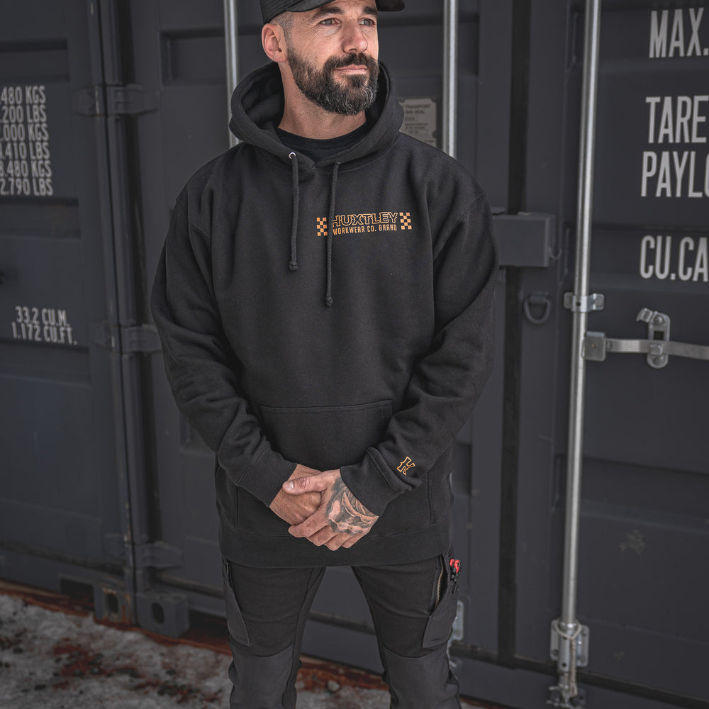 
                  
                    Full-body view of the Huxtley Work Hard Have Fun Hoodie in black, featuring orange checker graphics and bold chest branding. Built tough for the jobsite with clean lines and streetwear punch.
                  
                