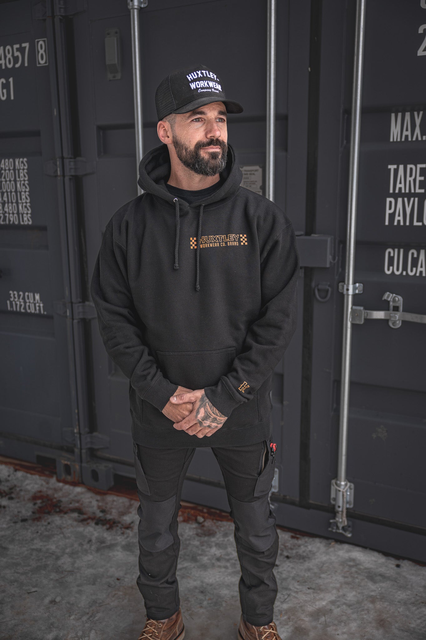 
                  
                    Full-body view of the Huxtley Work Hard Have Fun Hoodie in black, featuring orange checker graphics and bold chest branding. Built tough for the jobsite with clean lines and streetwear punch.
                  
                